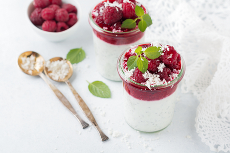 Layered raspberry smoothies with chia seeds, fresh raspberry and coconut on a light stone background. Useful dessert. Selective focus.の写真素材
