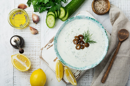 Traditional Greek sauce Tzatziki. Yogurt, cucumber, dill, garlic and salt oil in a ceramic bowl on a light wooden background. Rustic style. Selective focus. Top view.の写真素材