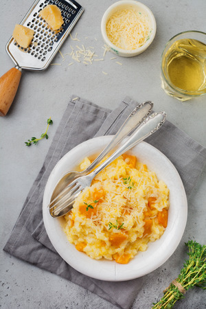 Pumpkin risotto with thyme, garlic, parmesan cheese and white wine on gray concrete or stone  background. Selective focus. Rustic style. Top view.の写真素材