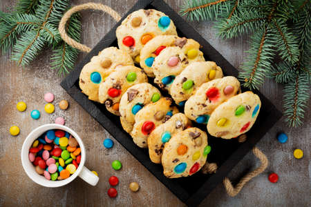 Children's cookies with colorful chocolate sweets in sugar glaze on brown concrete or stone background. Christmas card. Selective focus. Top view. Place for text.の写真素材