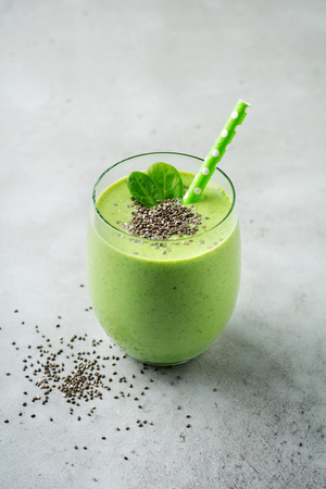 Vegetarian healthy green smoothie from avocado, spinach leaves, apple and chia seeds on gray concrete background. Selective focus. Space for text.の写真素材