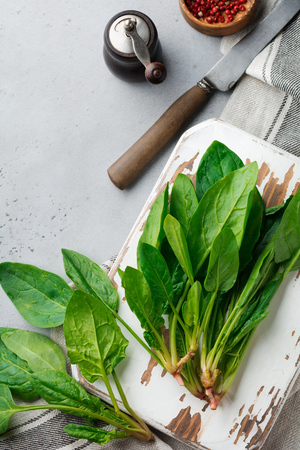Fresh raw spinach leaves on a wooden rustic stand on a gray old concrete background. Ingredients for salad. Selective focus. Top view. Copy space.の写真素材