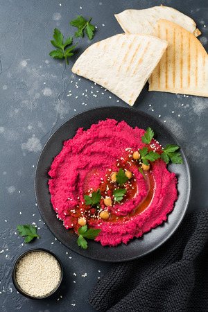 Homemade beetroot hummus in black ceramic dish on old dark concrete background. Selective focus. Top view.の写真素材