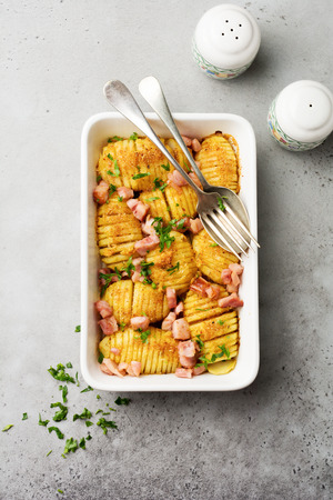 Baked potatoes with ham, herbs and breadcrumbs on gray light background. Scandinavian cuisine. Top view.の写真素材