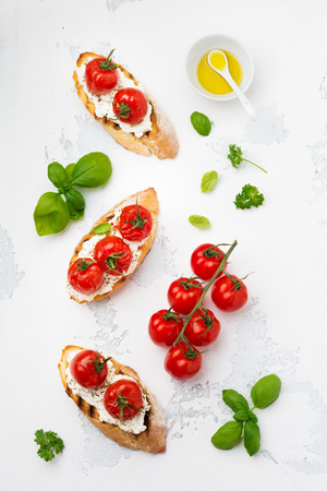 Sandwich with baked cherry tomatoes, garlic, olive oil and curd cheese on white background. Italian Cuisine. Top view.の写真素材