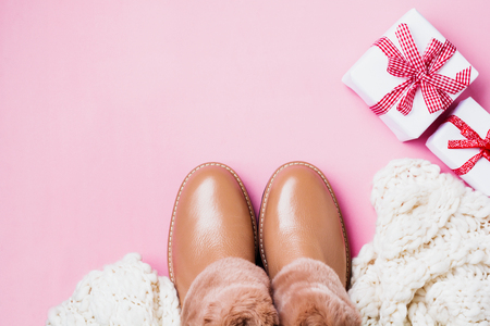 Leather women's warm shoes with fur, white scarf and gifts boxes on light pink background. ?oncept of the New Year season. Top view. Cope space.の写真素材