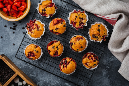 Strawberry chocolate cupcakes muffins on old wooden stand on concrete gray background. Top view.の写真素材
