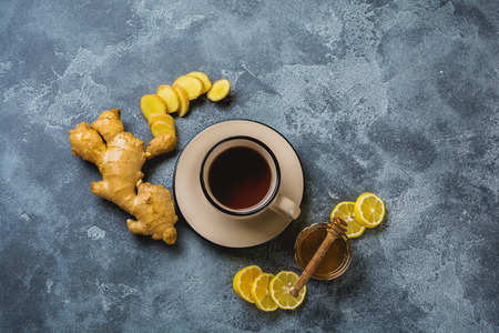 Cup of hot Ginger tea with lemon and honey on dark gray background. Top view. Copy space.の写真素材