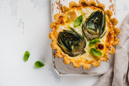 Homemade quiche tart with with artichoke on light wooden background. Vintage style. Top view.の写真素材