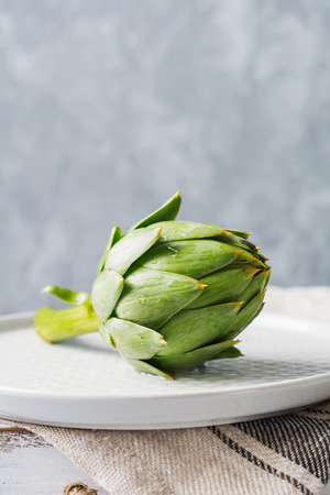 Raw whole organic wet green artichokes over gray texture background. Top view with spaceの写真素材