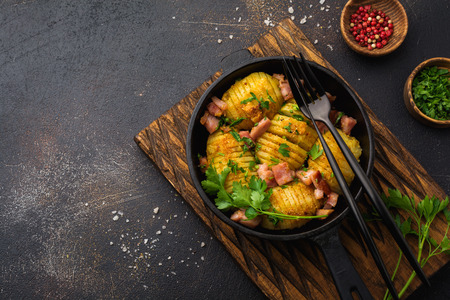Baked potatoes with ham, herbs and breadcrumbs on dark background. Scandinavian cuisine. Top view.の写真素材