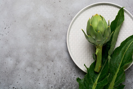 Raw whole organic wet green artichokes over gray texture background. Top view with spaceの写真素材