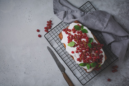 Bundt cake with glaze and red currant on gray concrete vintage background. Toned image. Top view.