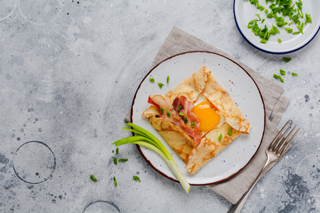 Crepe with fried egg, cheese, bacon and green onions for breakfast on a light gray concrete background.の写真素材