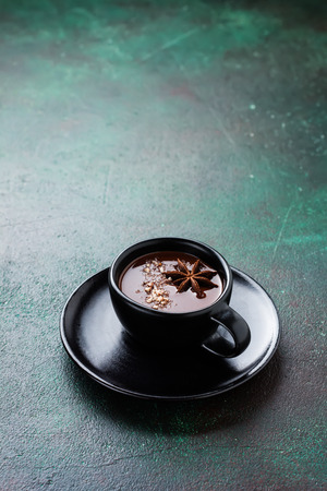 Hot chocolate with anise and nuts in black ceramic cup on old dark green concrete background. Selective focus.の写真素材