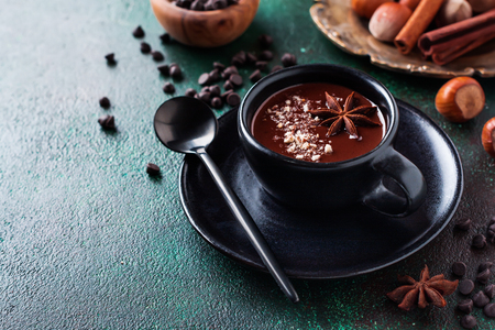 Hot chocolate with anise and nuts in black ceramic cup on old dark green concrete background. Selective focus.の写真素材