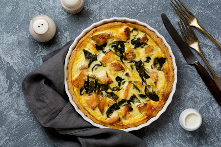 Homemade quiche tart with red fish and spinach on light wooden background. Vintage style. Top view.の写真素材