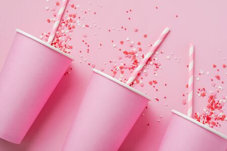 Three pink paper cup of coffee on pink paper light background. Zero waste concept. Flat lay.の写真素材