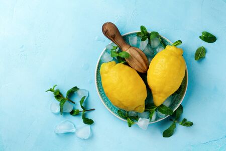 Two fresh lemons in blue plate on turquoise concrete background. Food background. Top view.の写真素材
