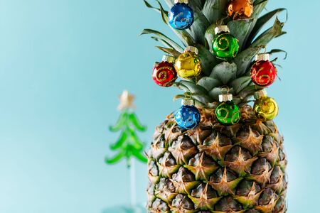 Christmas tree made of pineapple and colorful baubles on blue background, copy space. Card, decoration for new year party. の写真素材