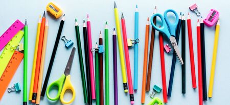 Colored pencils, scissors, notebook, ruler, pen, eraser, sharpener and more in glass. School and office stationery on light blue background. Concept back to school. Top view.の写真素材