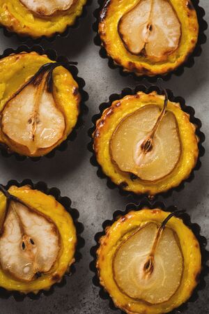 Pears and custard mini tarts on a dark gray concrete old table background. Top view.の写真素材