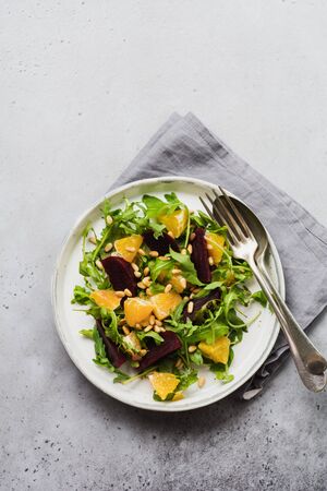 Beets, orange, pine nut, olive oil, feta cheese and arugula salad in ceramic plate on old concrete table background. Top view.の写真素材