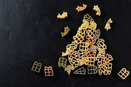 Fir-tree from Raw Christmas pasta on a black concrete background. Cooking concept. Top view with copy space.の写真素材