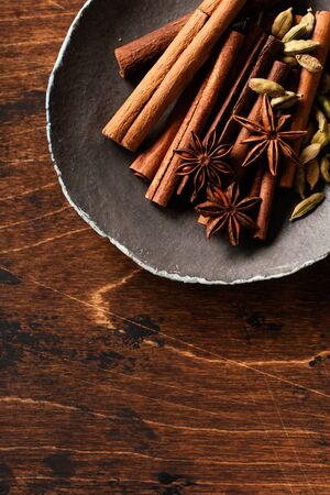 Assorted natural cinnamon sticks, cardamom grains, anise stars baking ingredients on a rustic brown background. Natural spices.の写真素材