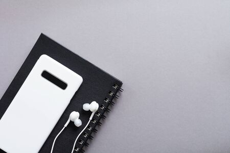 Modern White headphones, a notepad for notes and a mobile phone on a gray background. Minimalist style. Top view with copy space.の写真素材