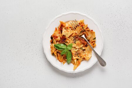 Pasta Maltagliati with classic tomato sauce, parmesan and basil on a rustic concrete light table background. Traditional Italian dish serving. Top view.の写真素材