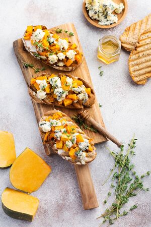 Baked pumpkin sandwich with dorblu cheese with blue mold, honey and thyme on a concrete old light background. Top view.の写真素材