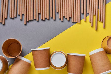 Drinking tubes made of paper and cornstarch, biodegradable material and eco paper glasses on yellow trend color 2021 background. Zero waste and plastic free concept. Top view.の写真素材
