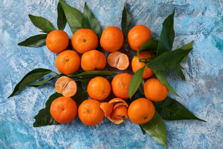 Tangerines or clementines plucked from leaves on a blue concrete background. Top view.