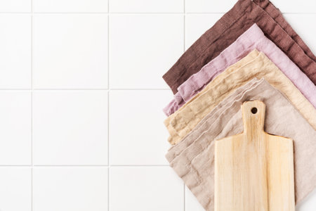 Cooking wooden cutting board and cotton kitchen napkin or towel over on white kitchen wall table. Food cooking template concept. Copy space background. Top view.の写真素材