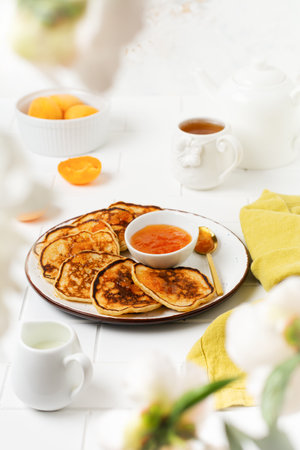Homemade delicious pancakes with fresh apricot fruit and jam on a light slate, stone or concrete...