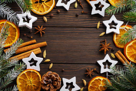 Christmas or New Year background. Fir branches with dried orange, cardamom and mulled wine spices, sprinkledon dark wooden background. Place for your text.の写真素材