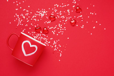 Red cup mug with with painted heart, sugar and chocolate hearts on scarlet or red background. Flat lay composition. Valentines Day concept. Top view, copy space.の写真素材