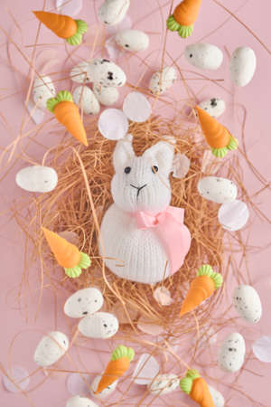 Flying quail eggs and White Rabbit in nest and sweet carrot on pink background. Easter minimal...