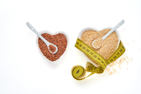 Quinoa grains with measuring tape and flaxseed in bowl of the shape of heart isolated on white background, top view. Concept of keto diet and proper nutrition.の写真素材