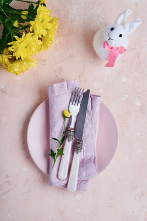 Easter spring greeting table setting with decorated with yellow chrysanthemums and cute rabbit on...