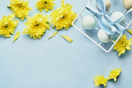 Eggs in white metal holder and flowers on blue background. Mock up. Spring Happy Easter holiday...