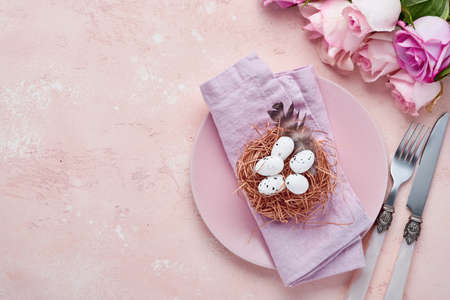 Easter spring greeting table setting with decorated with roses and nest with Easter eggs on blue...