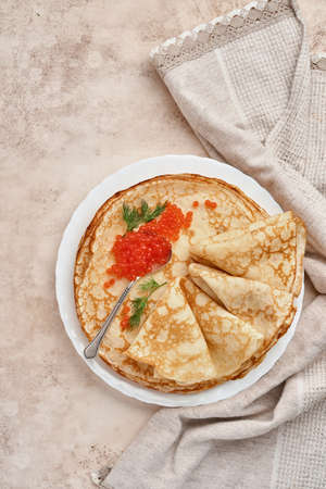 Crepes, thin pancakes, Russian pancakes with red caviar on gray plate. Marble background. Copy...