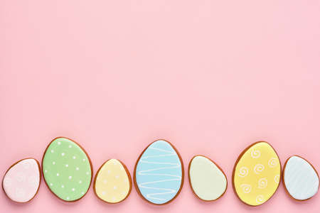 Easter greeting card with colorful rabbits, eggs, chickens and carrots gingerbread cookies on pink background with copy space. Mock up. Banner. Top view.の写真素材