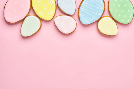 Easter greeting card with colorful rabbits, eggs, chickens and carrots gingerbread cookies on pink background with copy space. Mock up. Banner. Top view.の写真素材