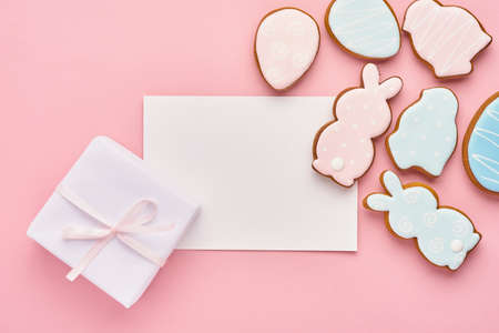 Easter greeting card with colorful rabbits, eggs, chickens and carrots gingerbread cookies on pink...