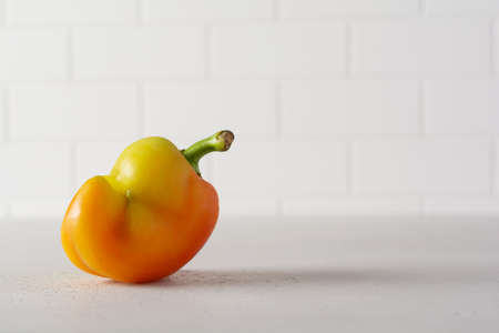 Ugly pepper that looks like a strange face on a light table. Funny, unnormal vegetable or food waste concept.の写真素材