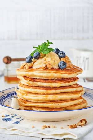 Pancakes with banana, walnut, honey and caramel for a breakfast. Selective focus.