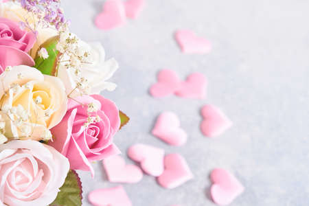 Festive composition with beautiful delicate roses flowers in pink round box with pink hearts on light gray background. Flat lay, copy space.の写真素材
